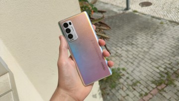 OPPO Find X3 Neo held in hand with the back facing the camera in front of a wall