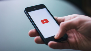 A person holding an iPhone with the YouTube app