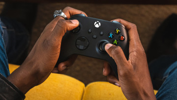 A person holding a black Xbox Wireless Controller