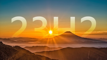 A picture showing the sun rising behind a mountain with a large 23H2 script