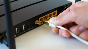 A person unplugging a WAN cable from a Wi-Fi router